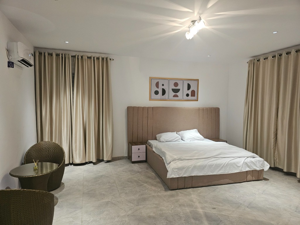 Master King suite with upholstered headboard, private woven lounge seating, and gold drapes